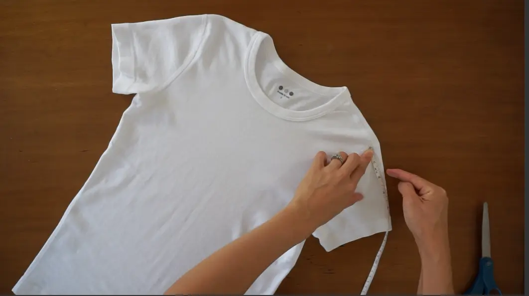 measure from the shoulder seam to determine where to start cutting on both sides of the t-shirt.