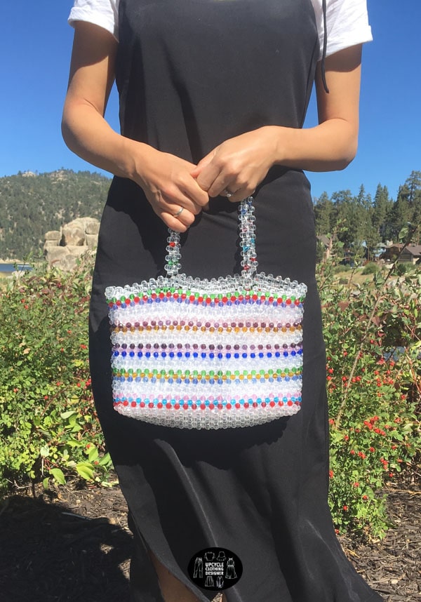 Beaded bag with handles. The striped pattern interchanges between colorful and clear beads.