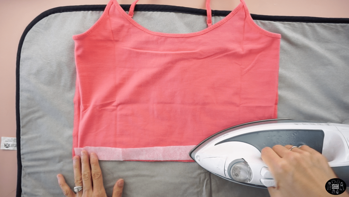 Use an iron to attach the interfacing along the wrong side of the cami top hemline.