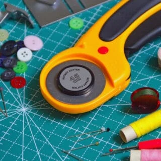 rotary cutter and fabric scissors on cutting board
