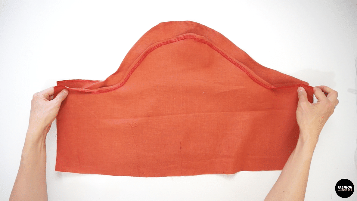 From the one notched side to the other notched side, fold ⅜” along the curved line and edge topstitch to create a tunnel. 