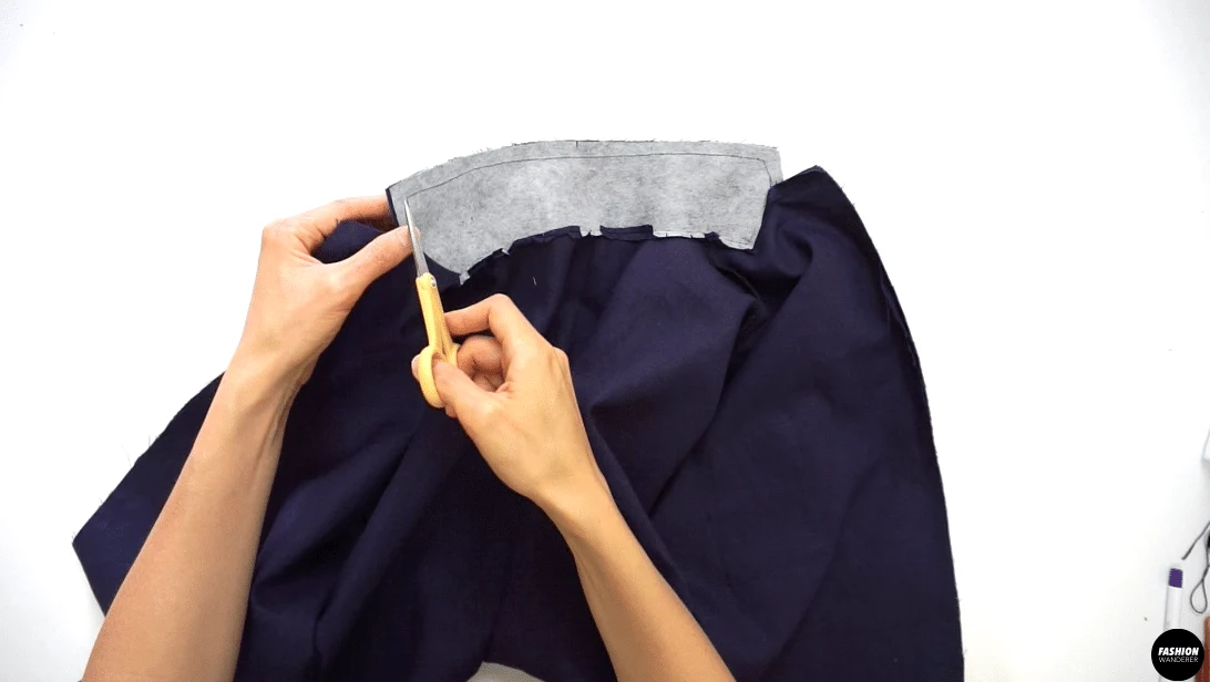 Trim the seam allowance to ¼” width and clip the corners and notches around the collar. Turn the facing to the inside. Press and shape the point and edges with an iron.