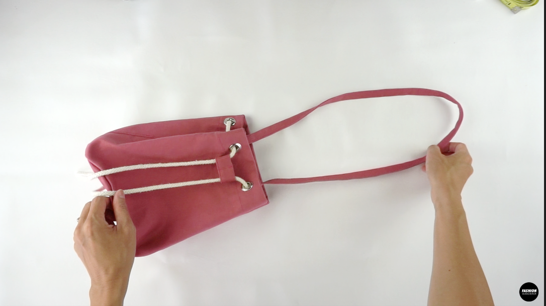 To finish the DIY bucket bag, insert the ends of drawstring through the grommets and weave through to the other end.
