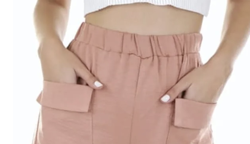 Close-up of pink high-waisted wide-leg pants with elastic waistband and flap pockets, styled with a white cropped tank top