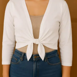 Woman wearing a white tie-front cardigan made from a t-shirt, tied at the waist over a beige tank top and blue jeans.