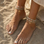 Feet in the sand with a boho inspired beaded anklet set