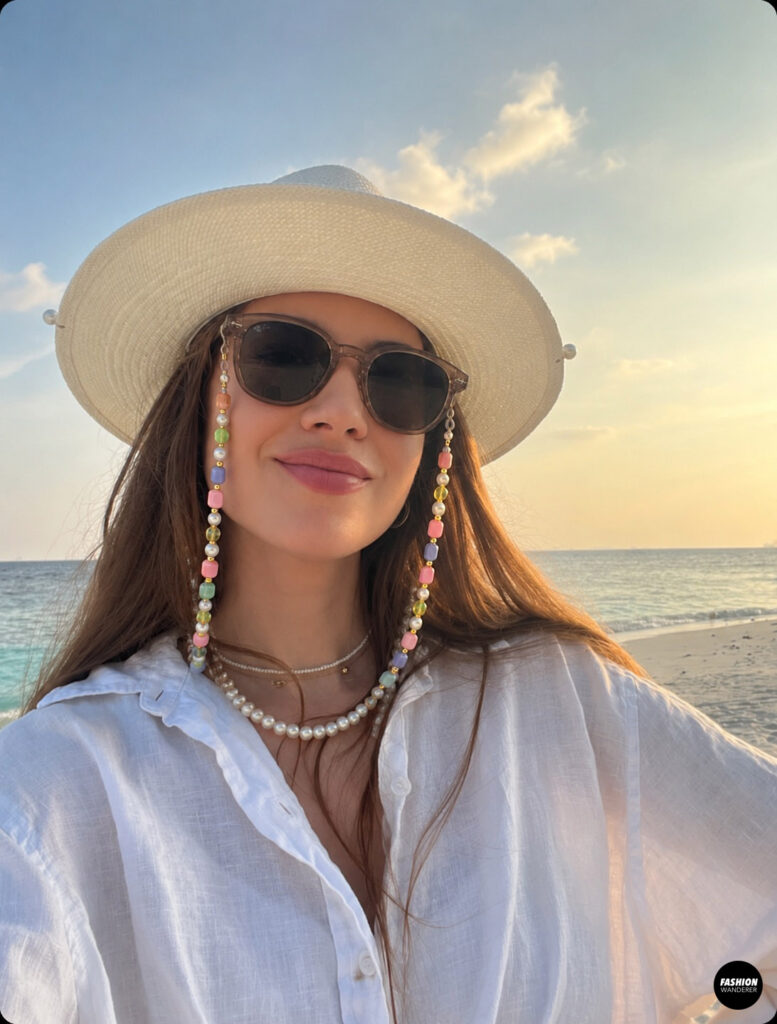 Woman at the beach wearing a sunhat with sunglasses and a chunky beaded sunglass chain.