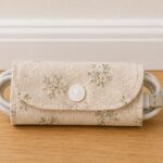 Handmade fabric cord organizer with snap closure holding a USB cable, an easy scrap fabric sewing project for organizing charging cords.