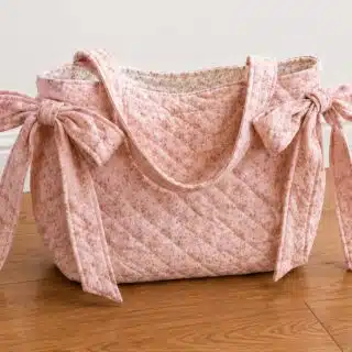 DIY quilted slouchy bow tote bag made with pink floral fabric, diamond quilting, long shoulder straps, and oversized side bows, an easy sewing project to make and sell.
